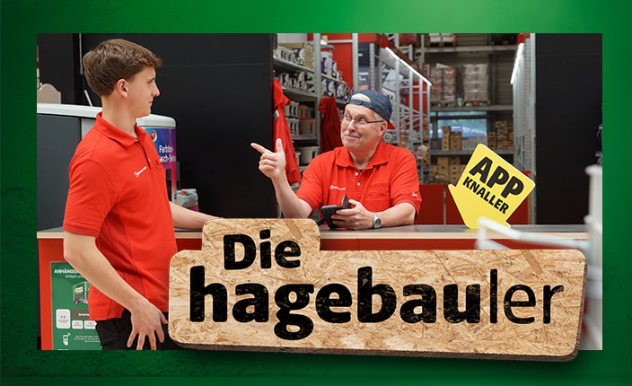 Zwei Baumarktmitarbeiter stehen an einem Tresen im Baumarkt und schauen sich an. Davor wird eine OSB-Platte mit der Aufschrift 