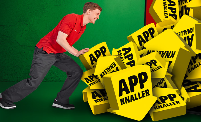 Ein Baumarktmitarbeiter schiebt zahlreiche gelbe Pfeile mit der Aufschrift „App Knaller“ in ein großes Handy hinein.